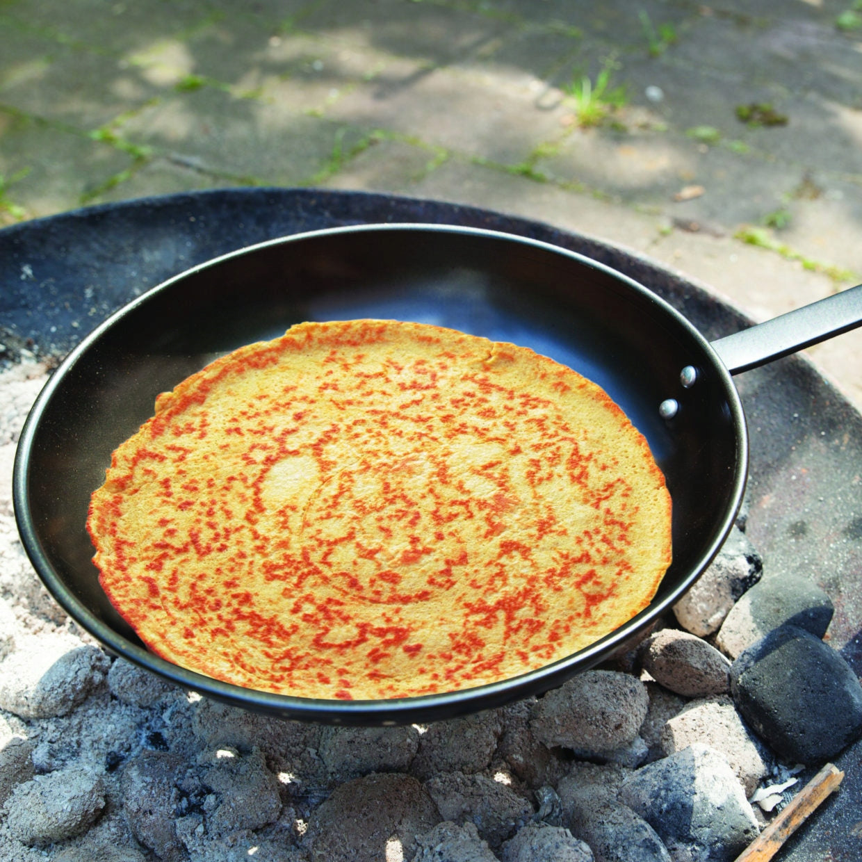 Pancake pan over fire grill Dominant color black